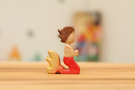 Kneeling Mermaid with short brown hair and red/yellow tail